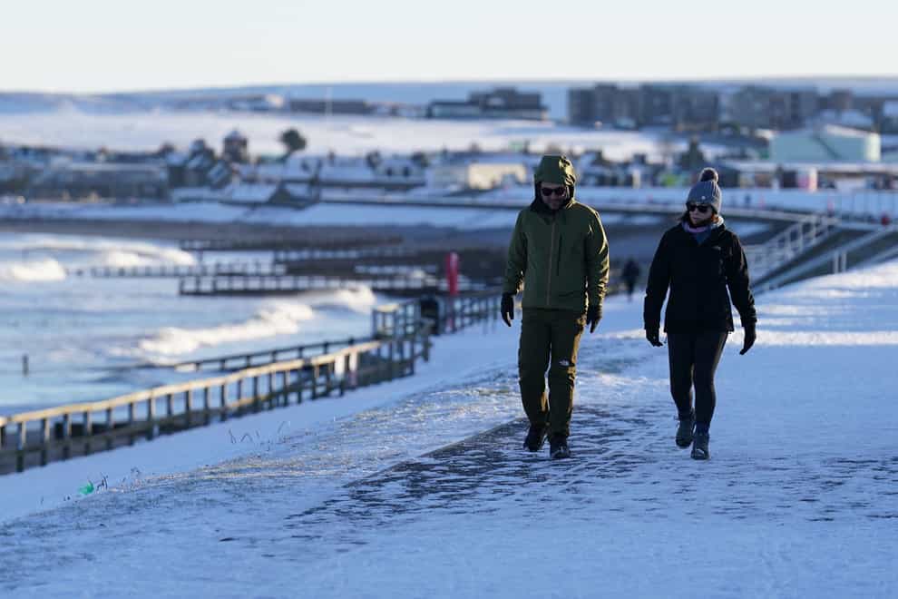 People walk along a snow-covered beach front in Aberdeen (Andrew Milligan/PA)