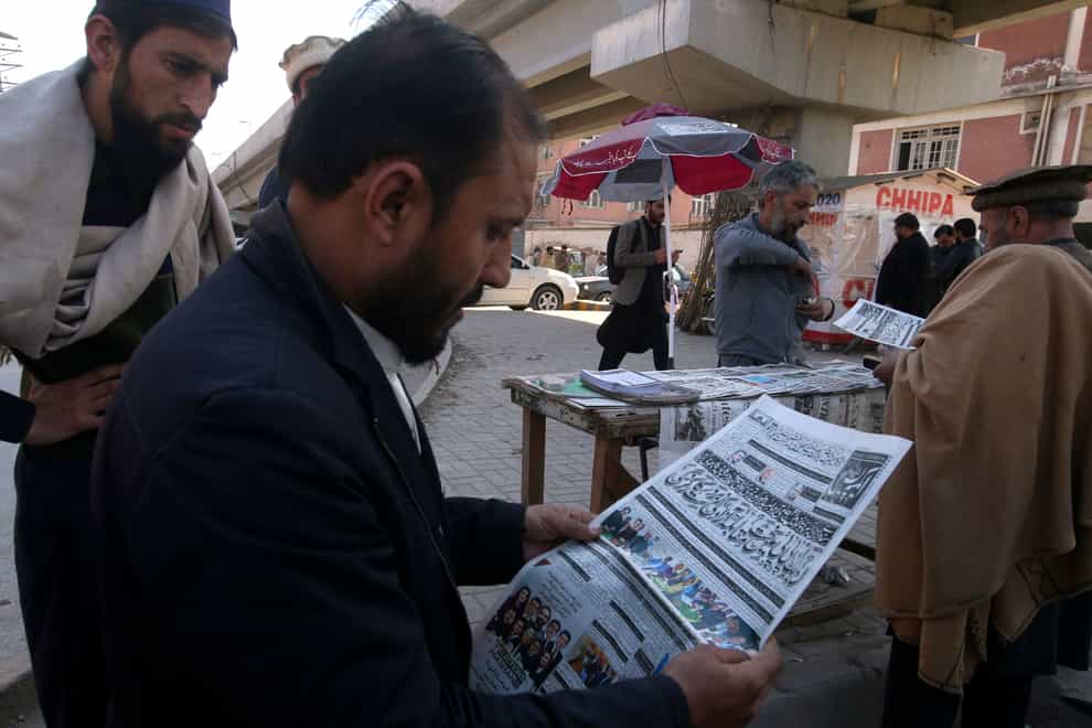 People read morning newspaper reporting the early results of parliamentary elections at a stall in Peshawar, Pakistan (Muhammad Sajjad/AP)