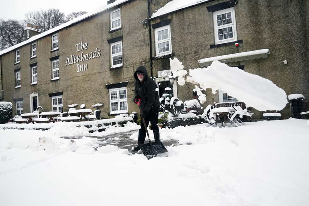 A person clears snow outside The Allenheads Inn in Northumberland (Owen Humphreys/PA)