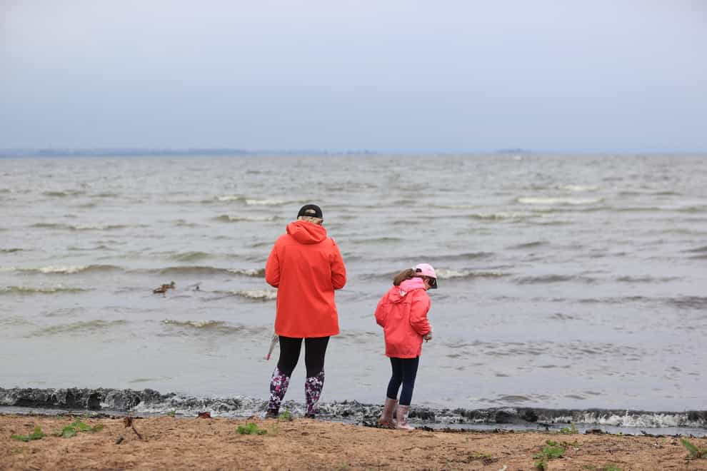A woman and young girl on the shore of Ballyronan beach on Lough Neagh (PA)