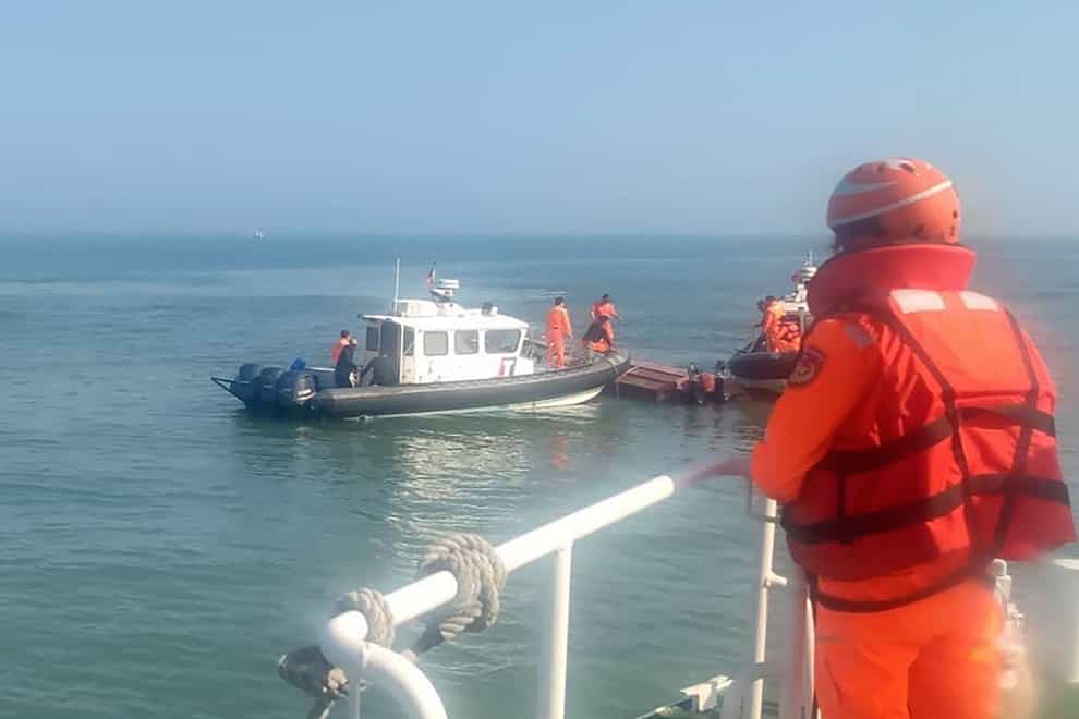 Taiwanese coastguards inspect the vessel that capsized during a chase off the coast of Kinmen archipelago (Taiwan Coast Guard Administration via AP)