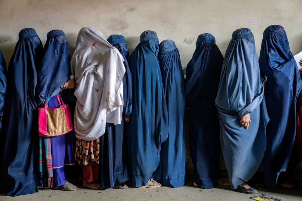 Afghan women wait to receive food rations distributed by a humanitarian aid group, in Kabul (Ebrahim Noroozi/AP)