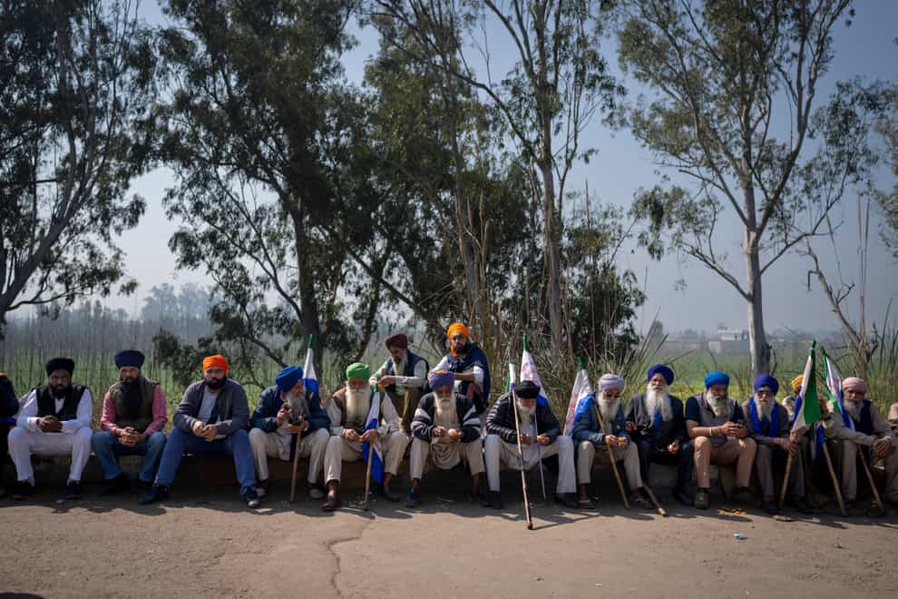 Protesting farmers bask in the morning sun as they block a major road after they were stopped by the police near Shambhu border that divides northern Punjab and Haryana states, almost 125 miles from New Delhi, India (Altaf Qadri/AP)