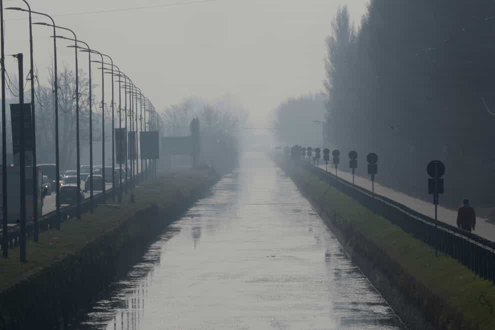 A man walks along the Naviglio Pavese canal shrouded in mist and smog in Milan, Italy (Luca Bruno/AP)