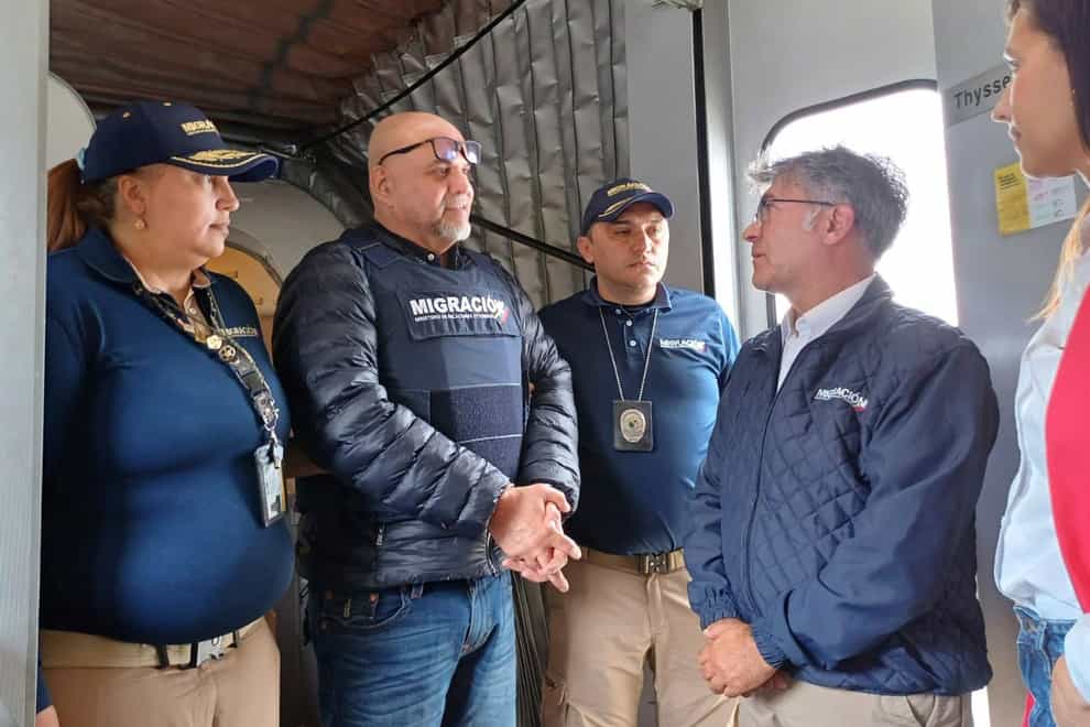 Former Colombian paramilitary leader, Salvatore Mancuso, centre, is met by immigration officials in Bogota (Colombian Immigration Agency via AP)