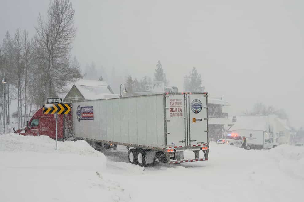 Vehicles make their way along a snow-covered road during a storm (Brooke Hess-Homeier/AP)