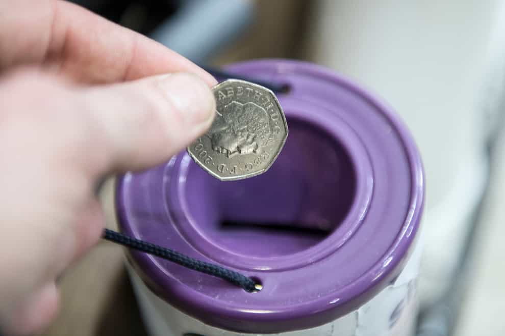 A coin is dropped into a charity collection container in London (PA)