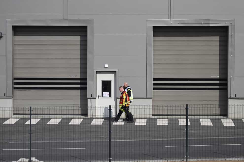 Fire department employees walk outside the Tesla car factory after production came to a standstill and workers were evacuated following a power outage, in Grünheide, Germany (Sebastian Gollnow/AP)