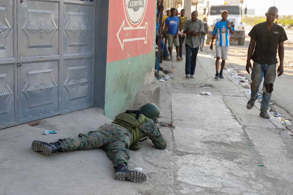 Pedestrians walk past a soldier guarding the area near the international airport in Port-au-Prince, Haiti (Odelyn Joseph/AP)