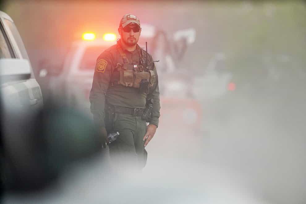 A US customs and border agent disappears into the dust as investigators drive to the site of the crash (Joel Martinez/The Monitor via AP)