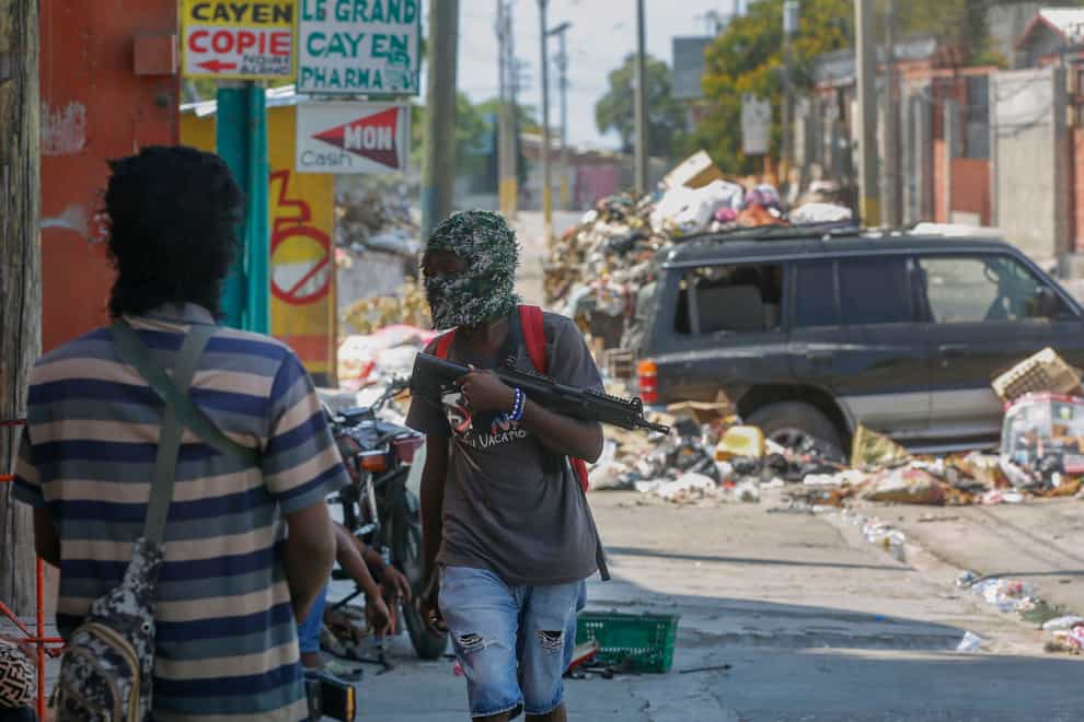 Armed members of the G9 and Family gang stand guard at their roadblock in the Delmas 6 neighborhood of Port-au-Prince, Haiti (Odelyn Joseph/AP)