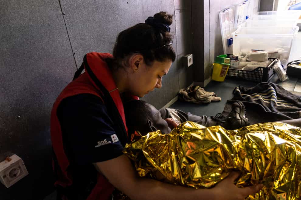 A rescue worker on the SOS Mediteranee’s humanitarian ship Ocean Viking attends to a rescued migrant (Johanna de Tessieres/SOS Mediteranee via AP)