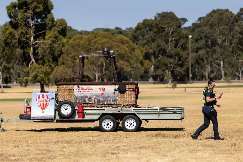 A police officer walks past a trailer with a hot-air balloon basket on it after the discovery of a man’s body at Yarra Bend Park in Melbourne (Diego Fedele/AAP Image via AP)