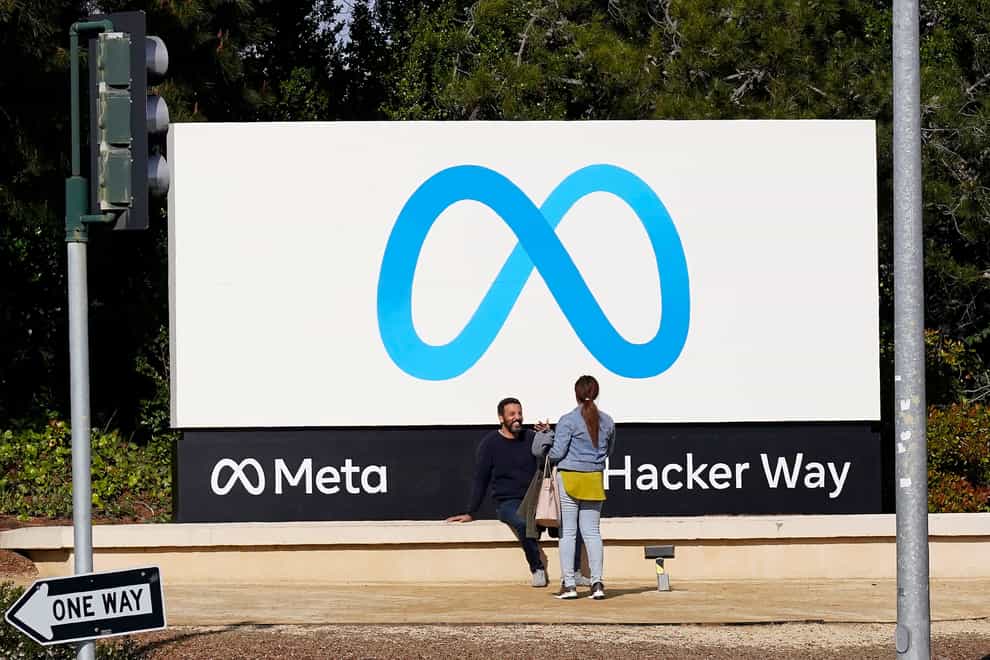 People talk near a Meta sign outside of the company’s headquarters in Menlo Park, California (Jeff Chiu, File/AP)