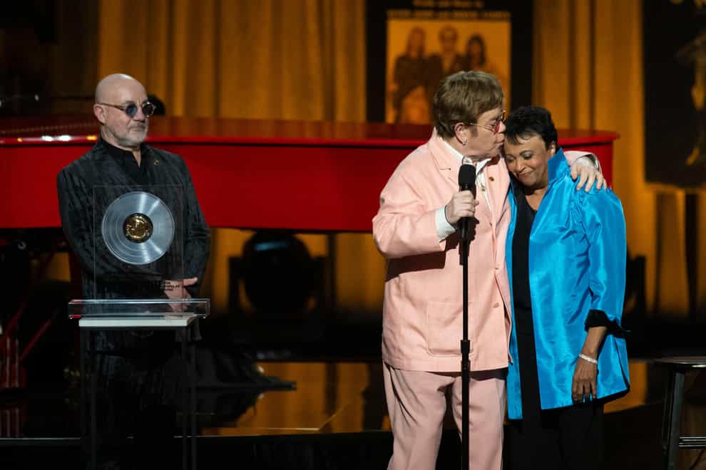 The singer, centre, collected the award together with his songwriting partner Bernie Taupin, left (Kevin Wolf/AP)