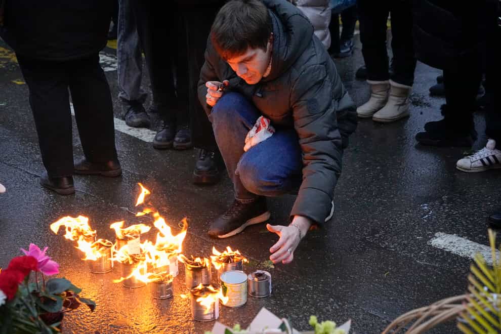 A man lights candles at the fence next to the Crocus City Hall in Moscow (Alexander Zemlianichenko/AP/PA)
