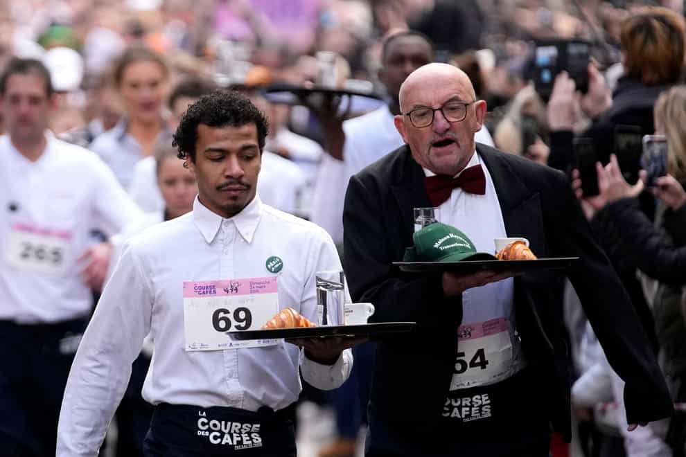 Waiters carry trays with a cup of coffee, a croissant and a glass of water (Christophe Ena/AP)