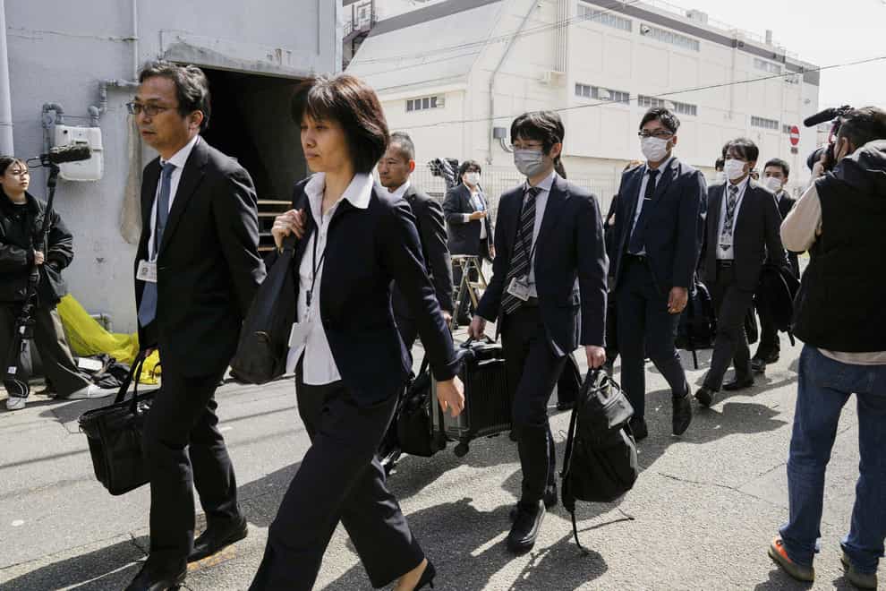 Japan’s health ministry officials walk towards the Osaka plant of Kobayashi Pharmaceutical (Yohei Fukai/AP)