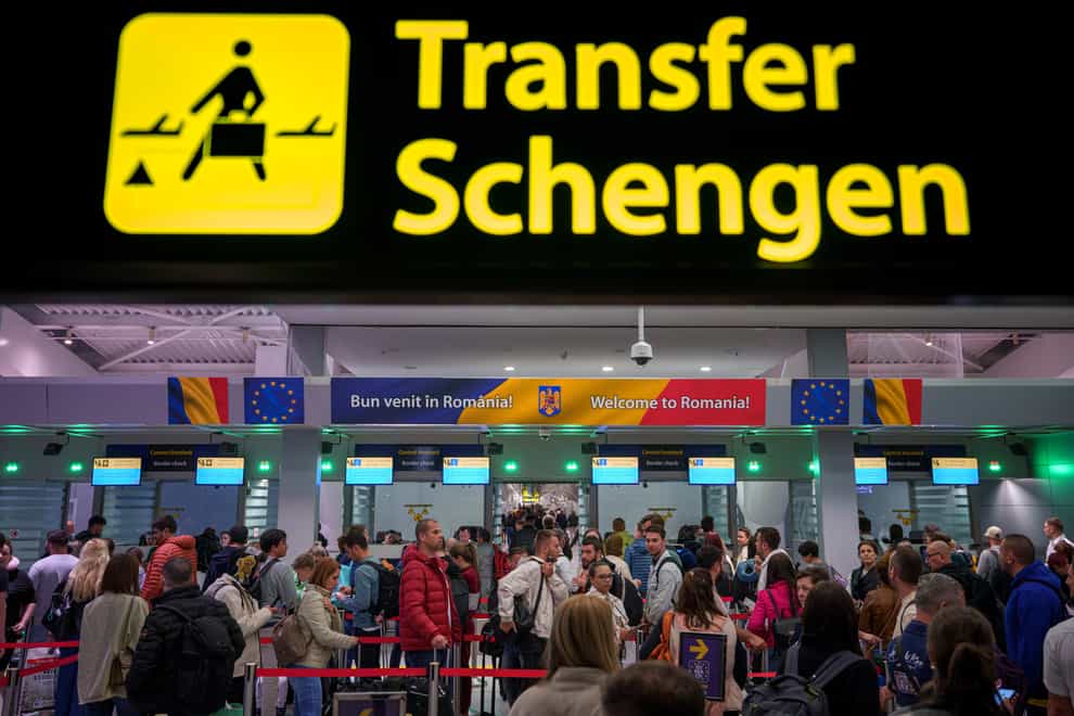 Passengers arriving at Henri Coanda International Airport in Romania pass under a Schengen Information sign (Andreea Alexandru/AP)