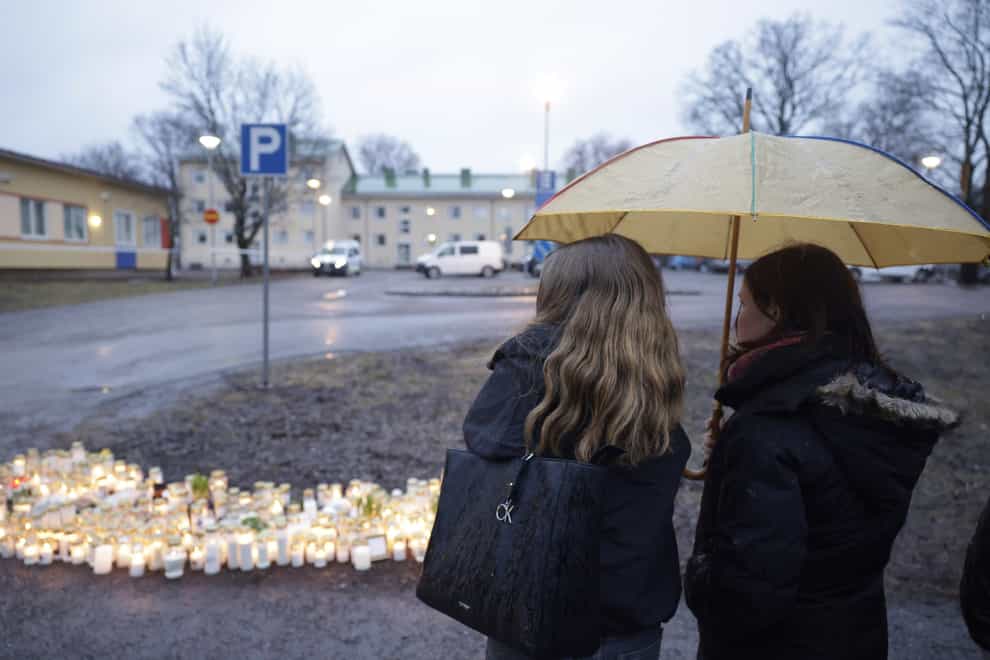 People bring candles and flowers at the school in Finland (Roni Rekomaa/Lehtikuva via AP)