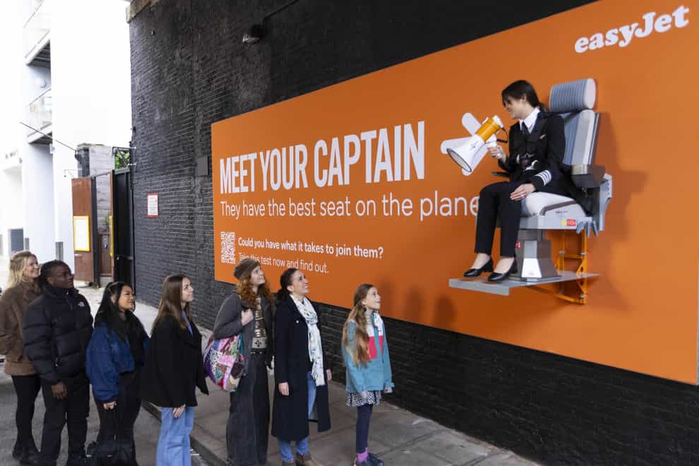 Pilot Sarah Ackerley sits on an interactive billboard in London at the launch of an easyJet campaign (David Parry/PA)