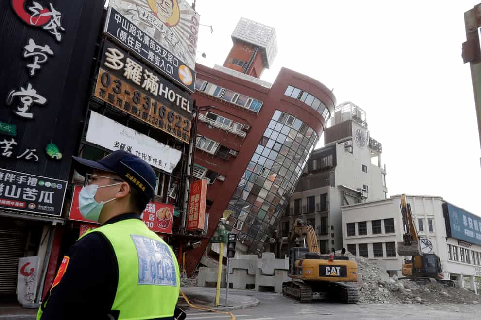 A police officer stands guard near a partially collapsed building a day after a powerful earthquake struck in Hualien City, eastern Taiwan (Chiang Ying-ying/AP)