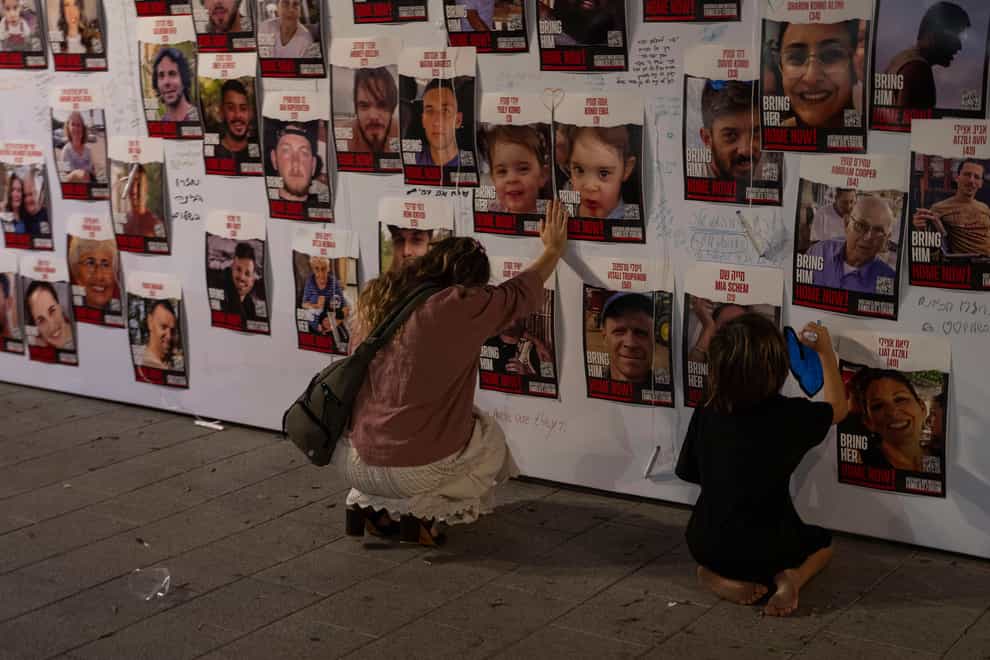 A woman touches photos of Israelis missing and held captive in Gaza, displayed on a wall in Tel Aviv (Petros Giannakouris/AP)