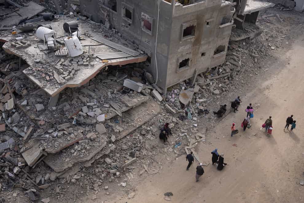 Palestinians walk through the destruction in the wake of an Israeli air and ground offensive in Khan Younis (Fatima Shbair/AP)