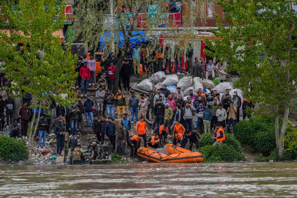 Rescuers prepare to search after a boat carrying people including children capsized in Jhelum river on the outskirts of Srinagar (Mukhtar Khan/AP)