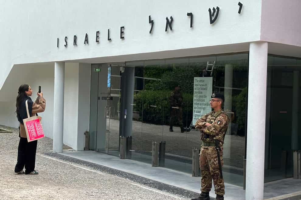 A woman takes a photo as an Italian soldier patrols the Israeli national pavilion at the Biennale contemporary art fair in Venice (Colleen Barry/AP)
