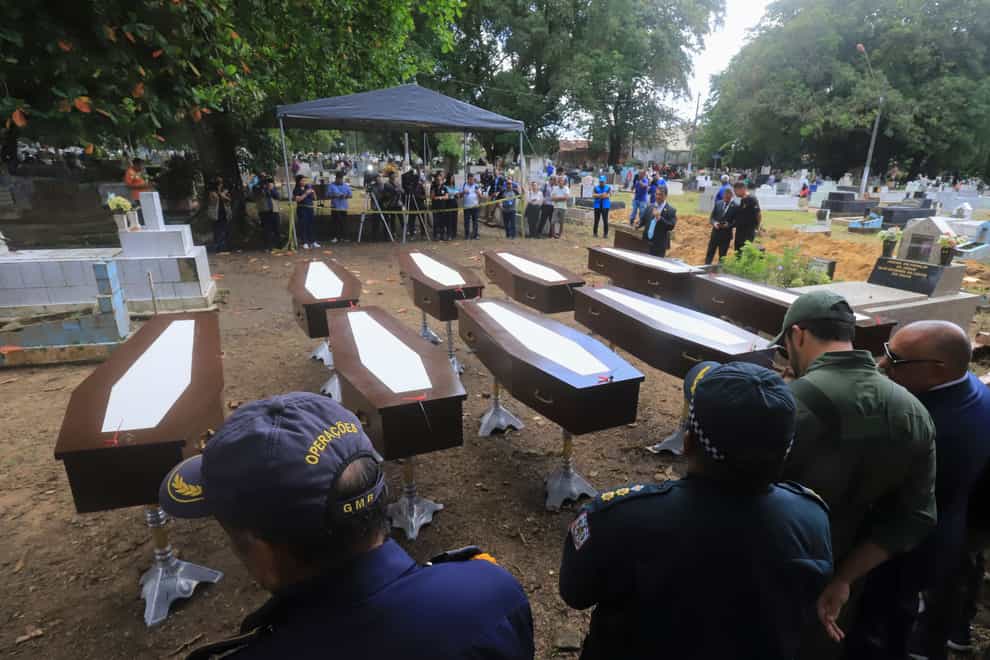 Authorities stand next to the nine coffins that contain the remains of unidentified migrants, at the Sao Jorge cemetery, in Belem, Para state, Brazil (Paulo Santos/AP)