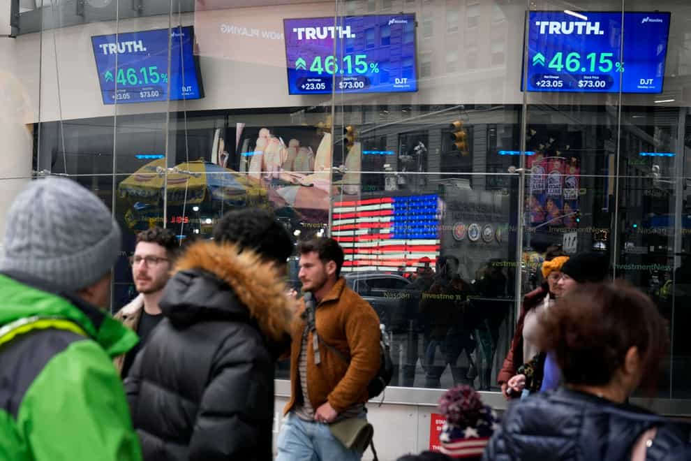 Pedestrians walk past the Nasdaq building as the stock price of Trump Media & Technology Group Corp is displayed on screens in March (Frank Franklin/AP)