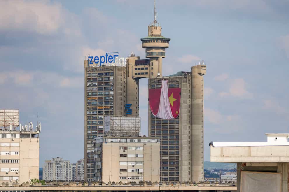 Workers hang on ropes to install a giant Chinese national flag on a skyscraper that is a symbolic gateway leading into the city from the airport, in Belgrade, Serbia (Darko Vojinovic/AP)