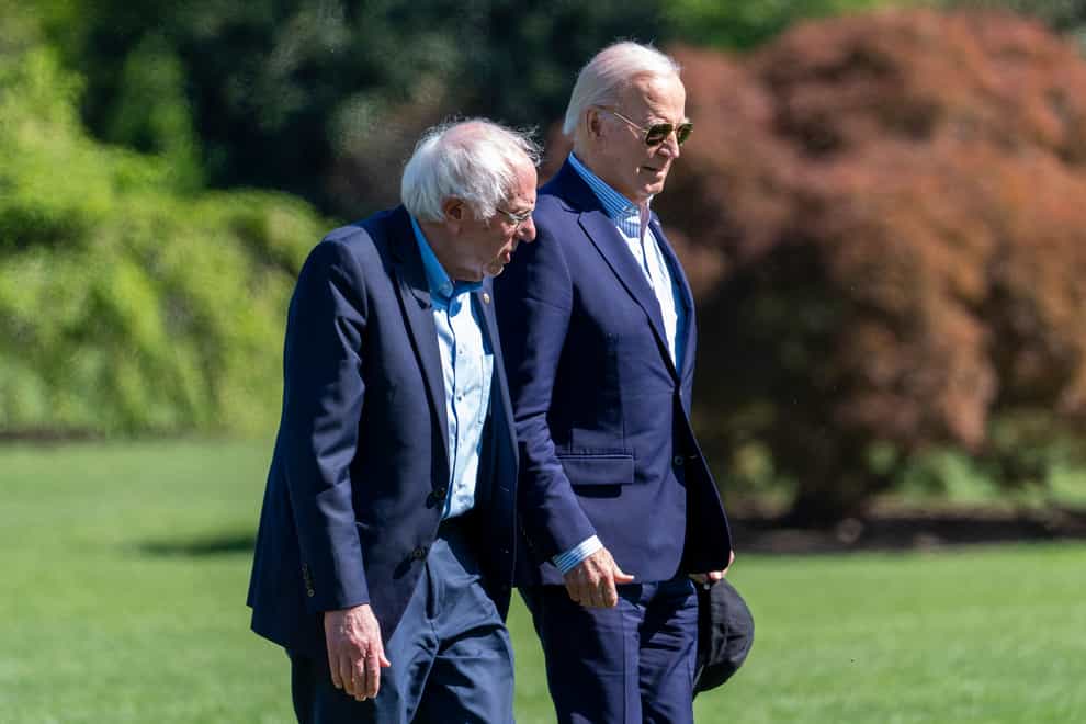 President Joe Biden, right, and Senator Bernie Sanders walk from Marine One upon arrival on the South Lawn of the White House in April (Alex Brandon/AP)